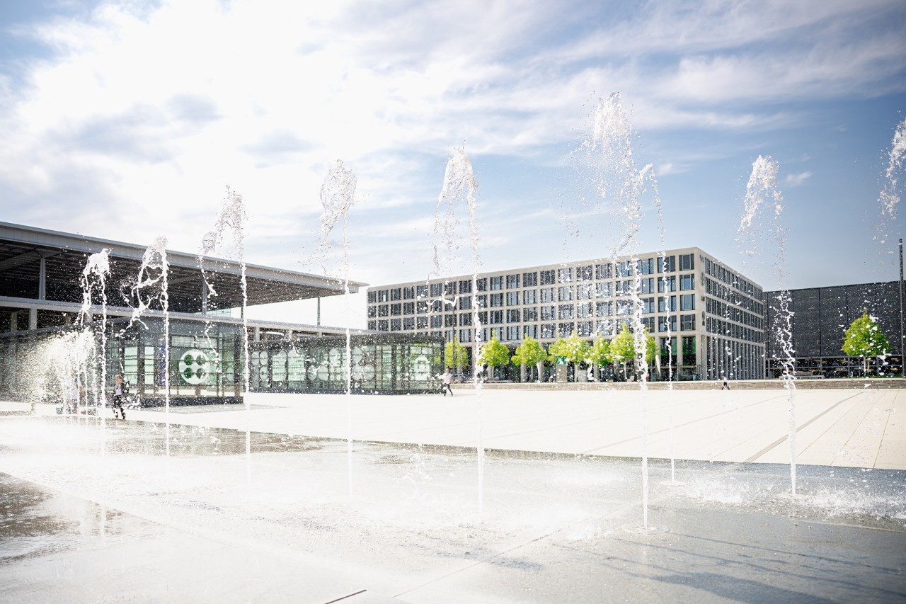 Willy-Brandt-Platz vor dem Terminal 1. Die Sonne scheint, der Springbrunnen läuft. ©Ekaterina Zershchikova / Flughafen Berlin Brandenburg GmbH